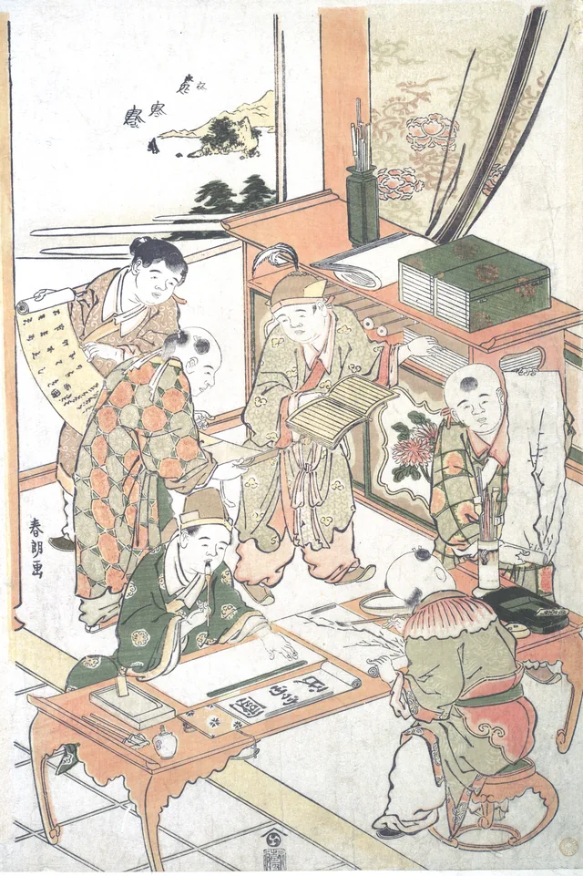Hokusai's print of boys at a writing lesson: one holds up a sheet of characters while the others write and paint at low desks.